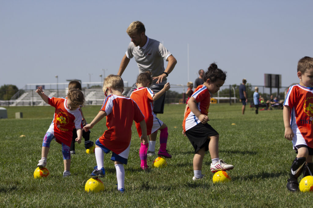 TinyTykes young players learning fundamental skills with coaches on camp